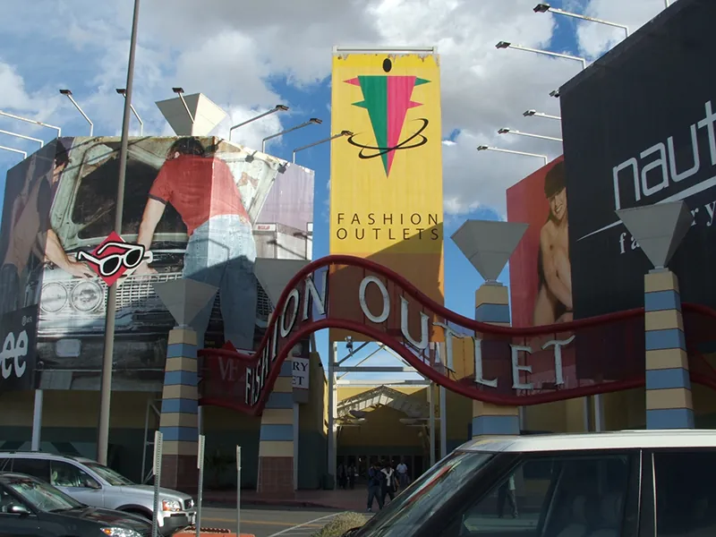 The words Fashion Outlet are over the entrance way to an outlet. Large stores are on either side of the sign.