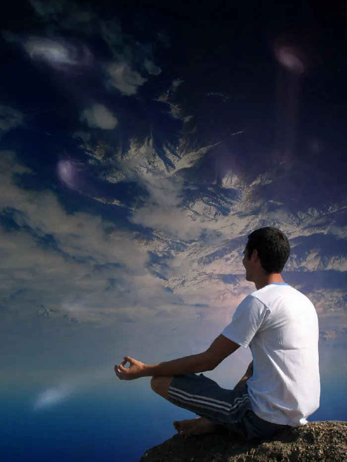 A man sitting on the top of a stone practicing meditation.