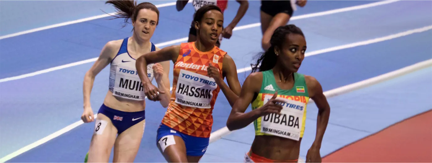 Three runners are close together during a race on a track.