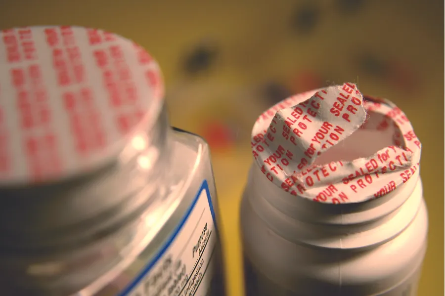 A photograph shows two pill bottles covered with tamper-proof seals; one seal is intact and one seal is broken.