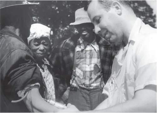 Photo of individual receiving a shot from a healthcare worker while two other individuals look on.