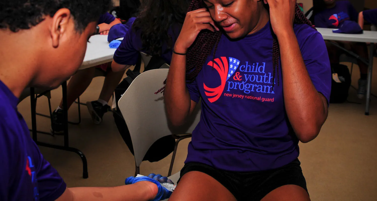 Photo of individual administering an EpiPen to the side of another individual’s leg.