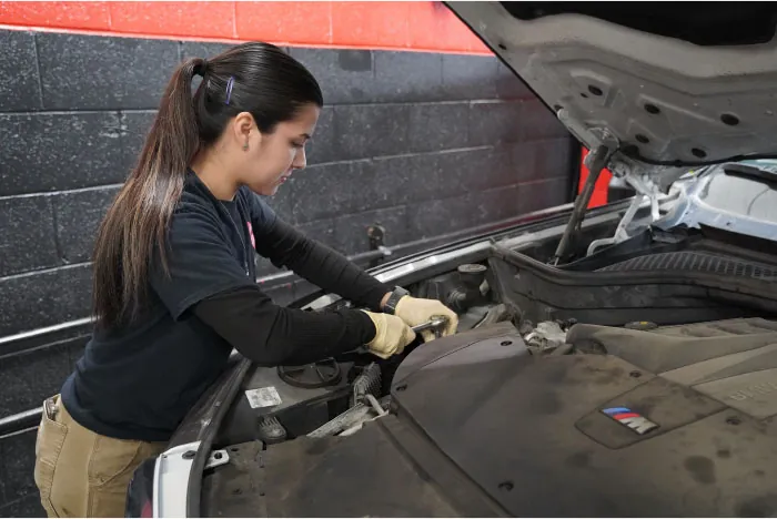 Photo of individual working under the hood of a vehicle.