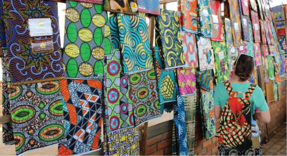 Photo of a person looking at many different fabric prints hanging on a wall.