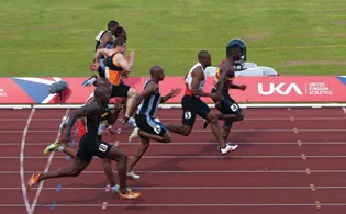 A photograph of 8 male runners in a track race.