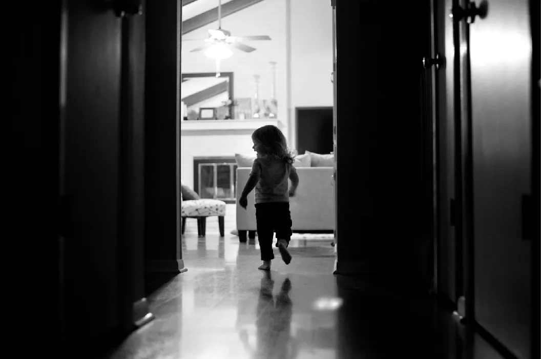 A small child runs through a hallway inside a house.