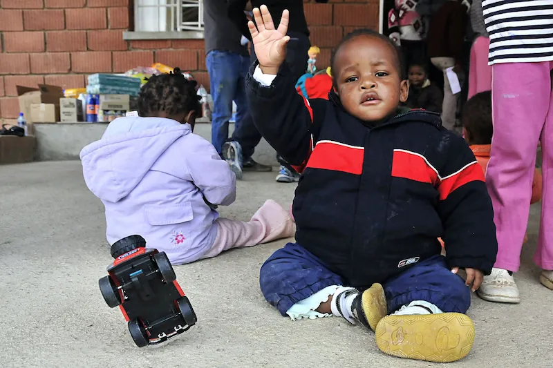 A photo of two young children sitting side by side but not facing each other.