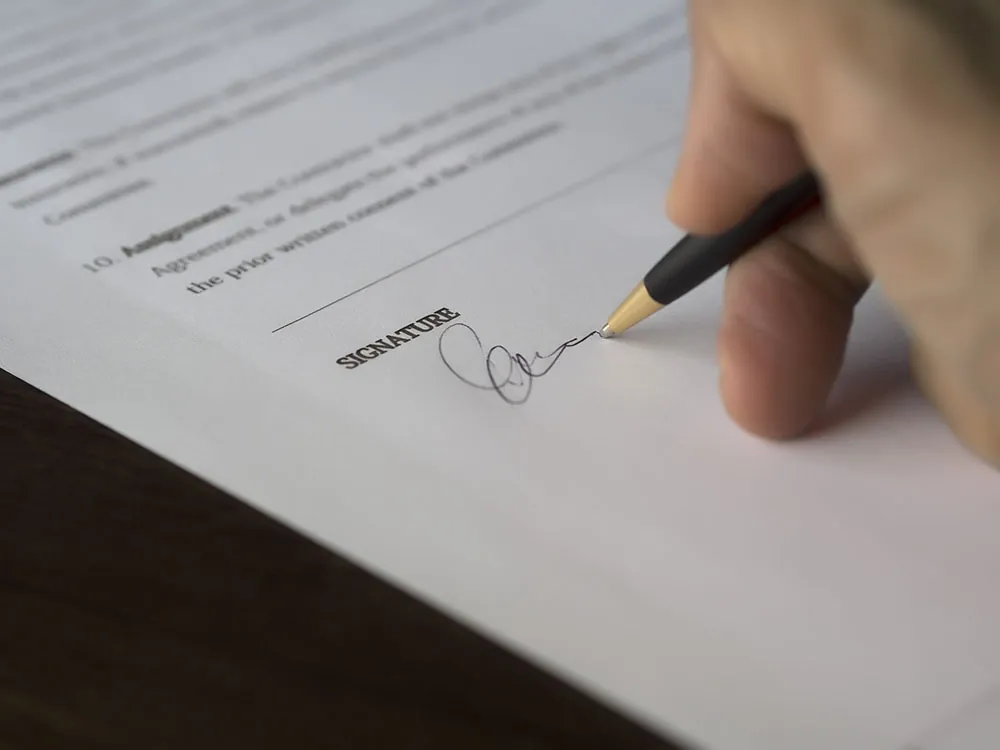 A photo shows someone signing a contract.