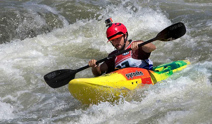 A kayaker wearing a helmet is riding through whitewater.