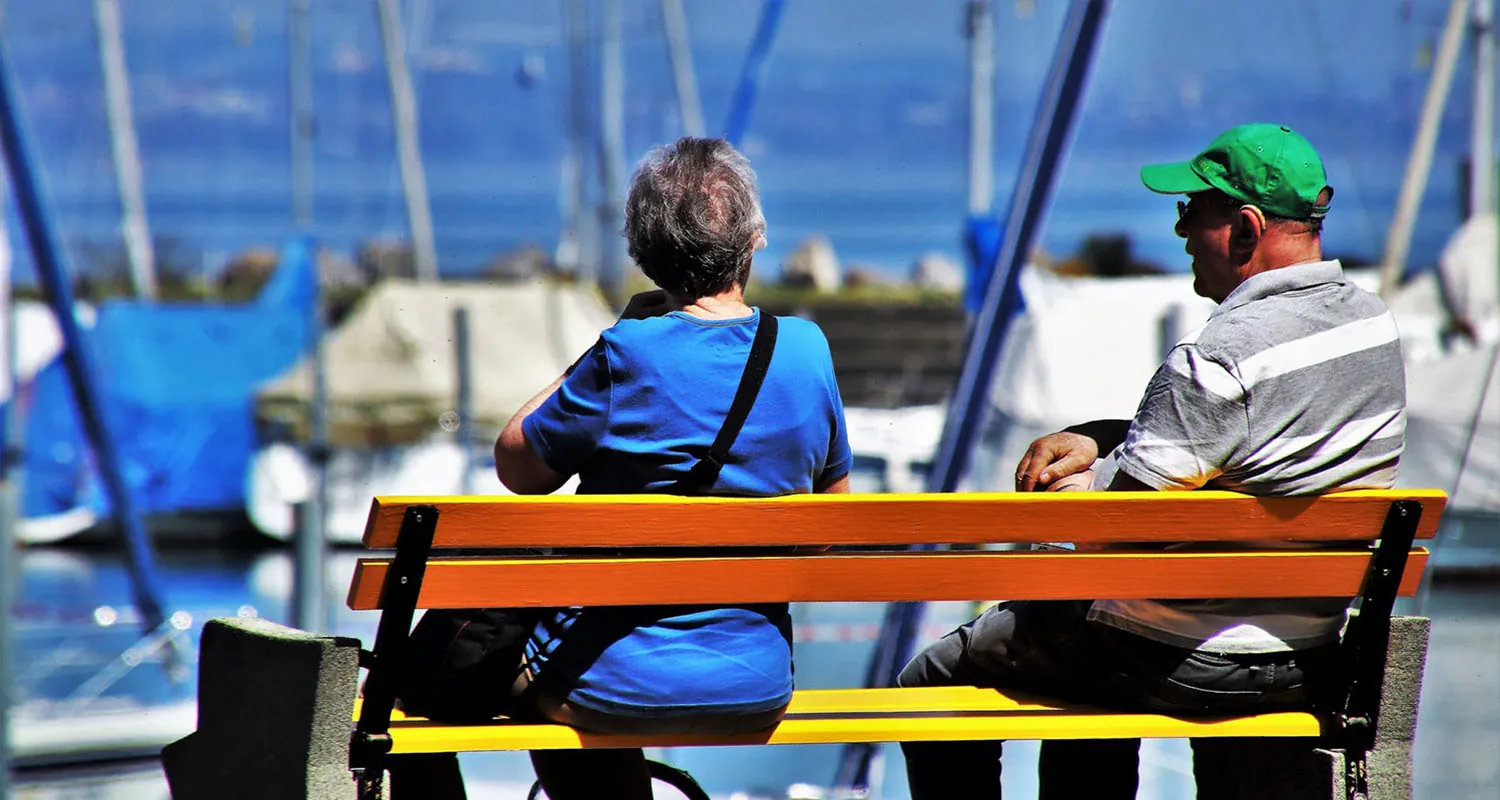 A photograph shows two older adults sitting on a bench.