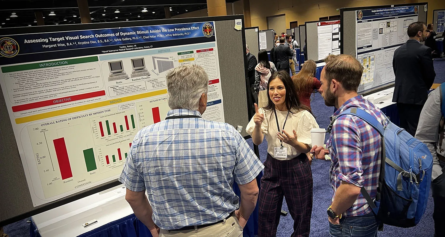 People having a conversation in front of a display of statistics.