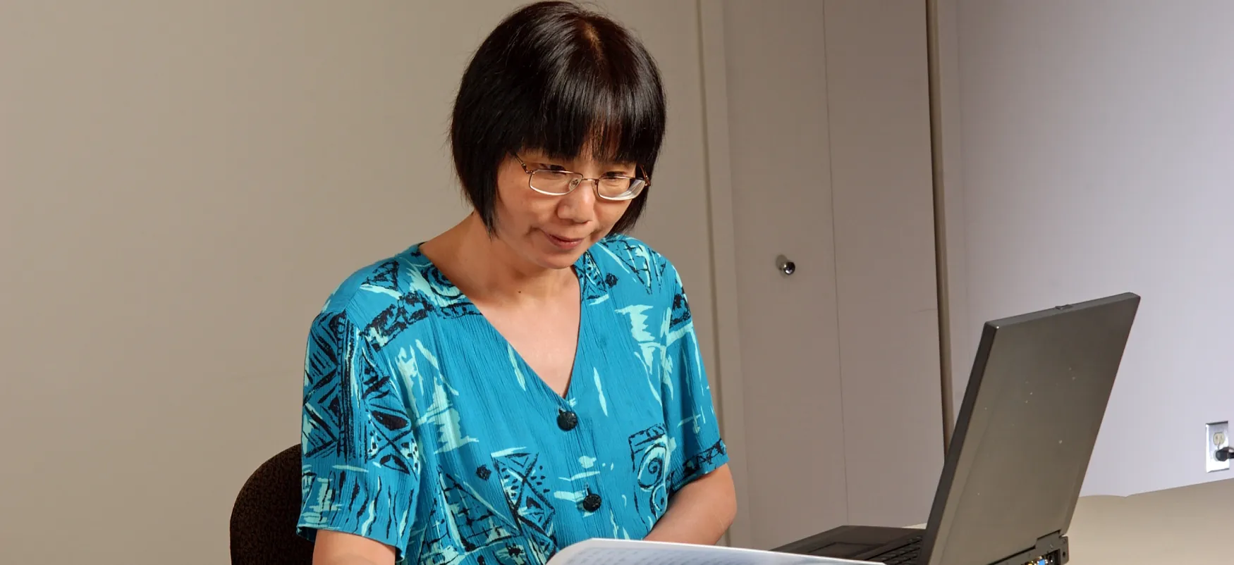 An analyst examines statistics on a computer and paper printout.