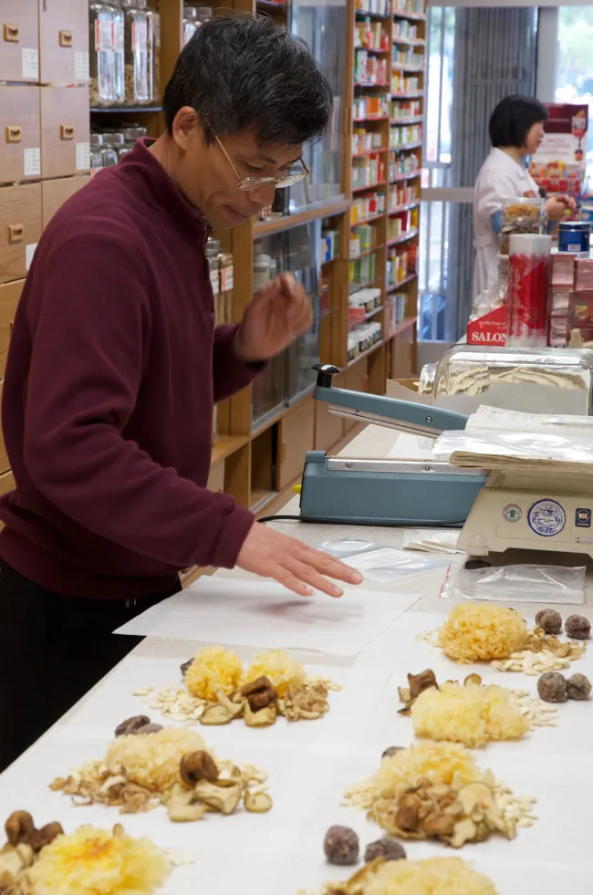 A man measuring out herbs for use in Traditional Chinese Medicine.