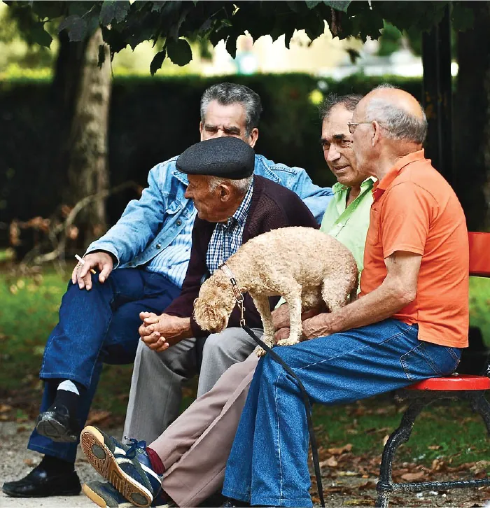 Four older men sit on a park bench.