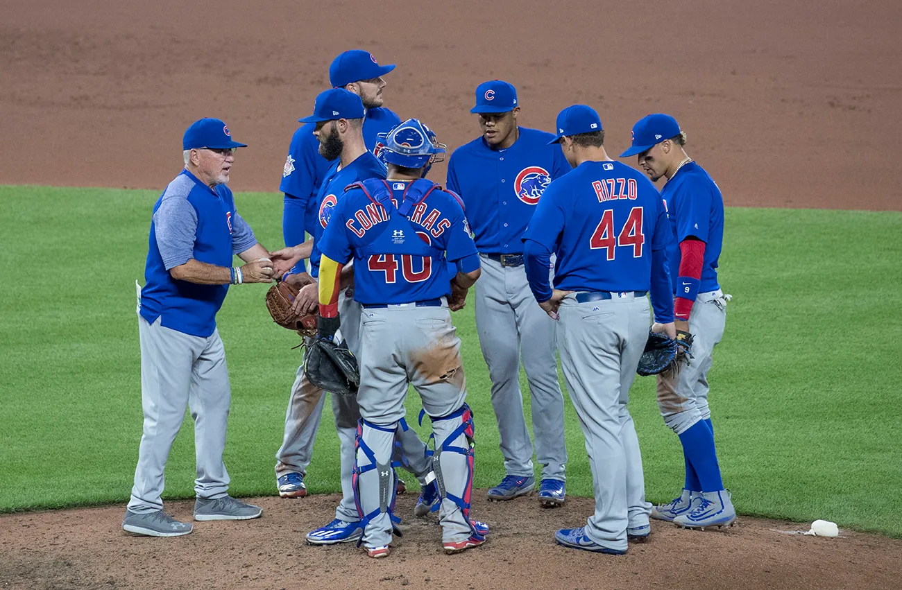 A photo shows Joe Madden, manager of the Chicago Cubs baseball team at pitcher mound, talking to the team.