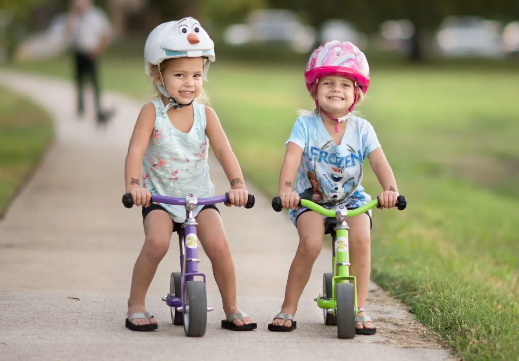 A photograph shows two children riding bicycles and wearing bicycle helmets.