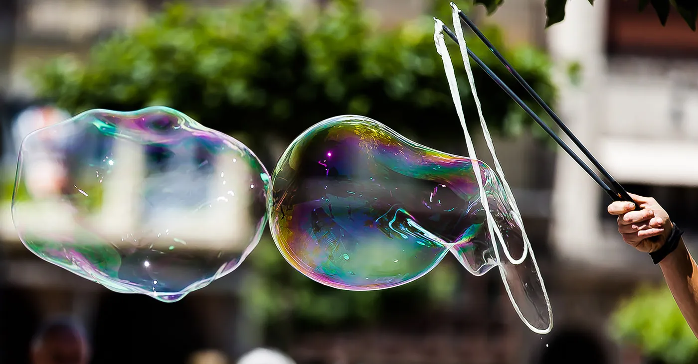 The reflection of large two soap bubbles created by a man.
