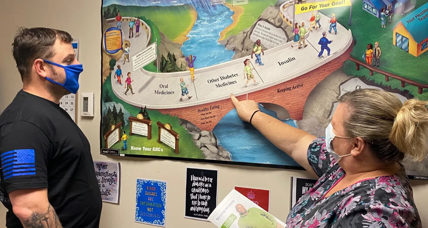 Photo of masked nurse pointing to a colorful painting while another masked individual looks on and listens.