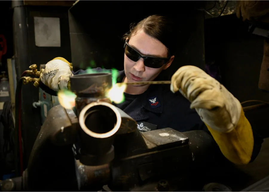 Photo of an individual wearing safety glasses and gloves while welding.