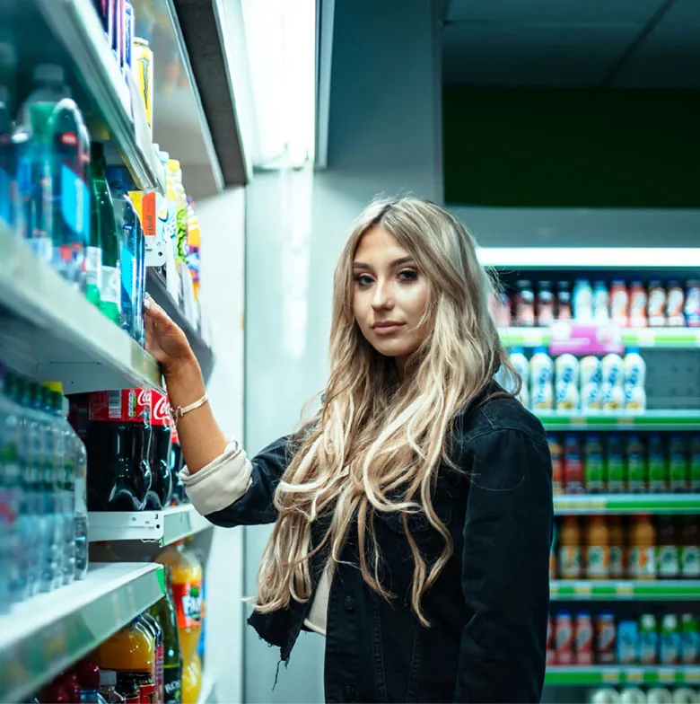 A young person smiling at the camera while shopping in the supermarket.