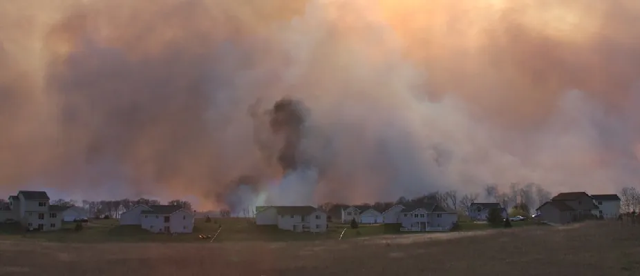 Smoggy and smokey air is visible above a neighborhood of houses.