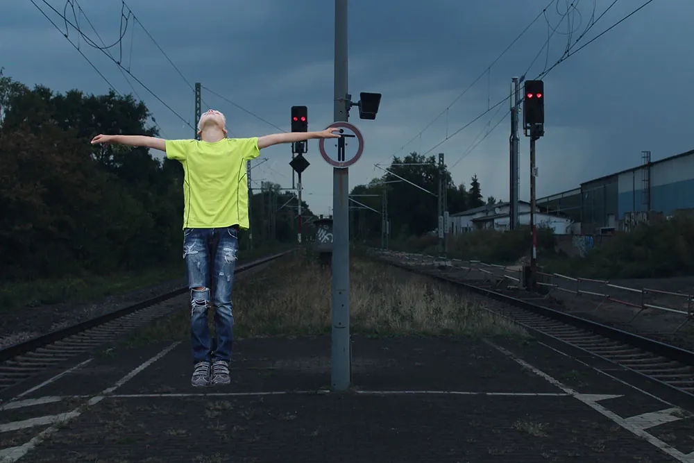 Child stands on train tracks at night.