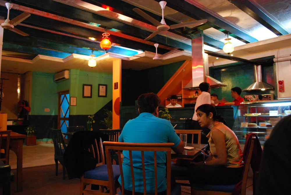 A man and a woman are shown talking at a table in a café.