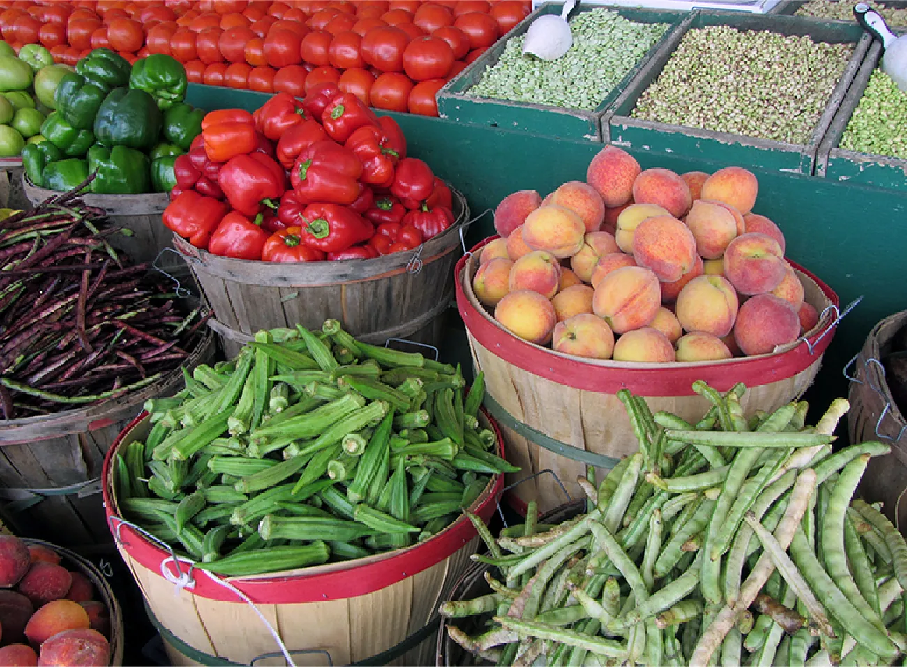 This is a photograph of various organic vegetables in baskets at a farmer's market.