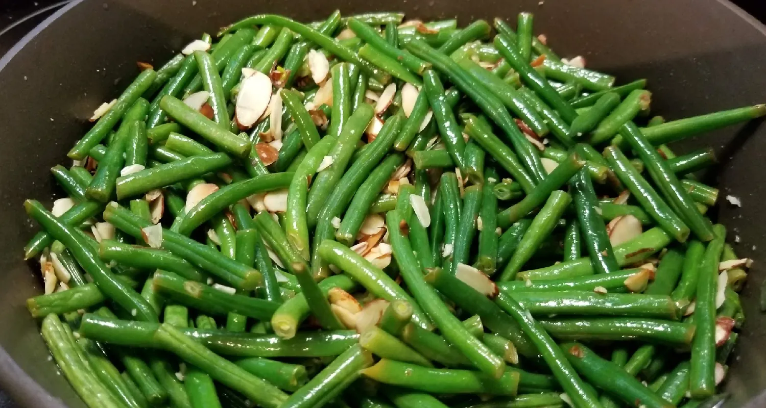 A large bowl contains green beans sprinkled with almond slices.