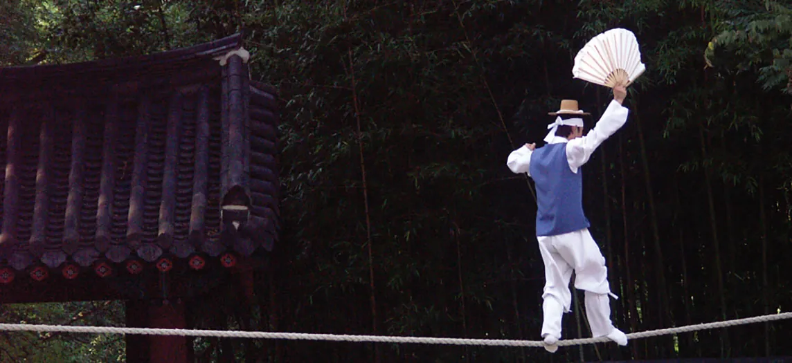 This photograph shows a man balancing on a tightrope.