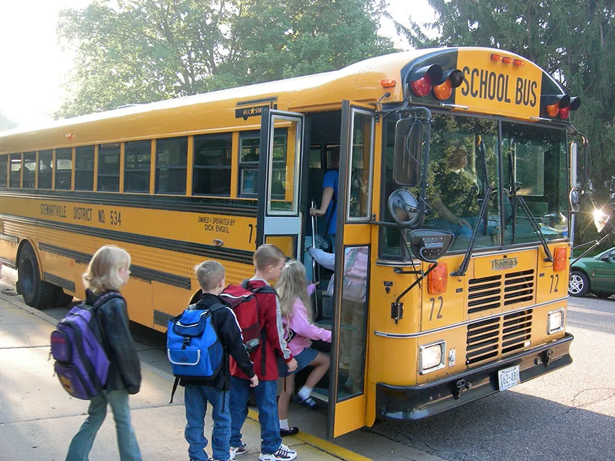 A group of children getting on a school bus.