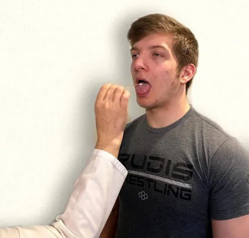 Photo of simulated patient having a cotton swab placed on his tongue by nurse