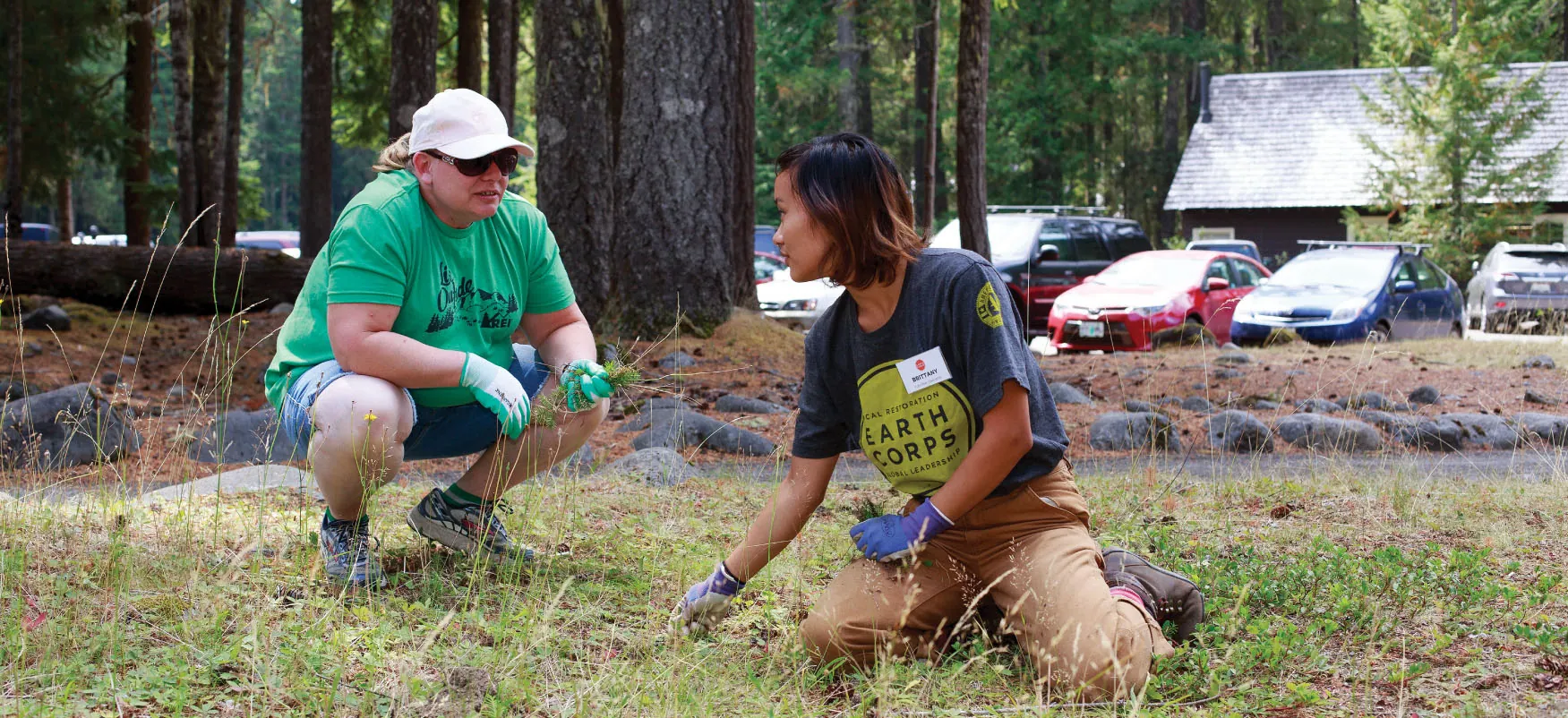 Photo of two individuals pulling weeds in a park.