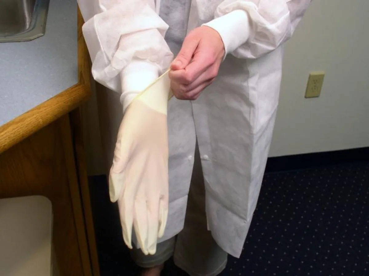 A photograph shows a healthcare worker putting on a glove.