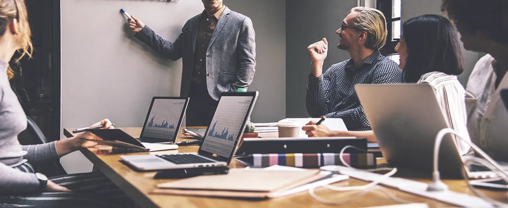 Picture of a woman at a desk working on a computer and writing in a notebook.