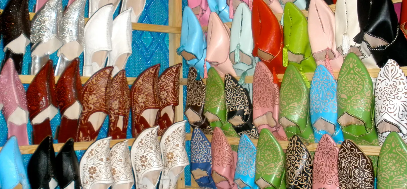 This photo shows many different pairs of shoes in various colors. The shoes appear to be hanging from a wall by cords.