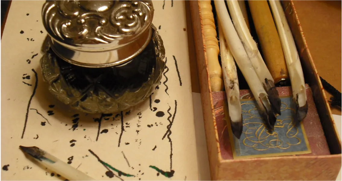 A picture of a few feather quills with an ink jar. 