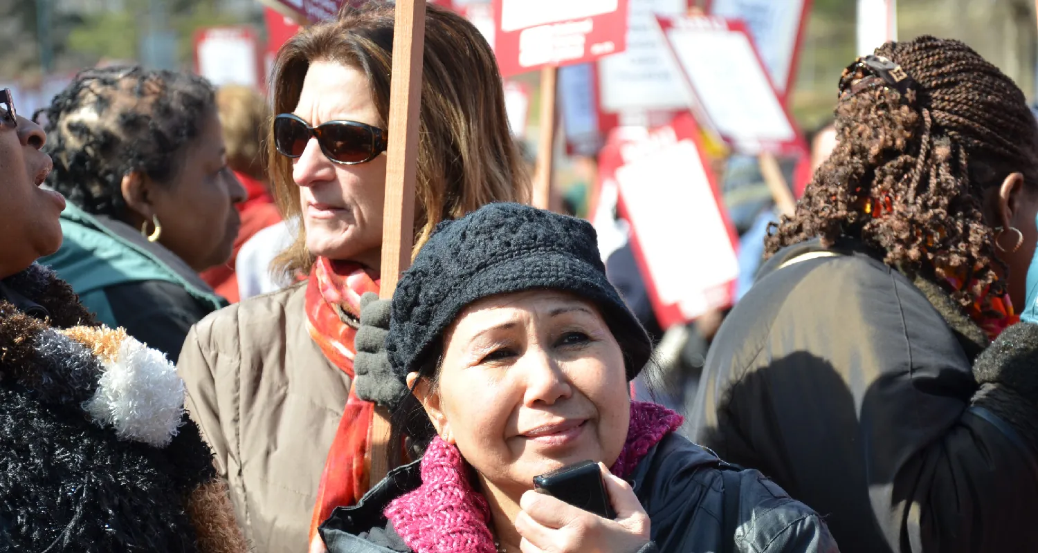 Protesters stand holding signs during a demonstration outdors.