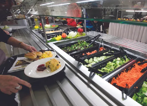 Food at a cafeteria with glass shielding over the food.