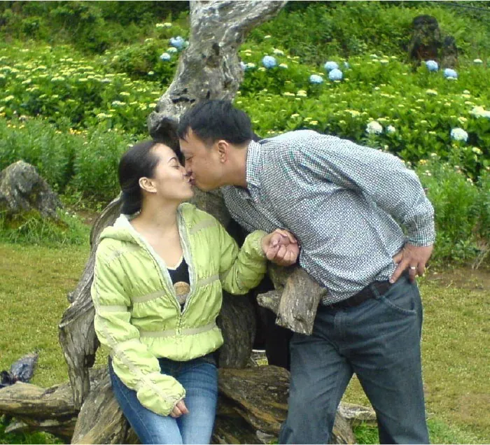 A couple hold hands and kiss.