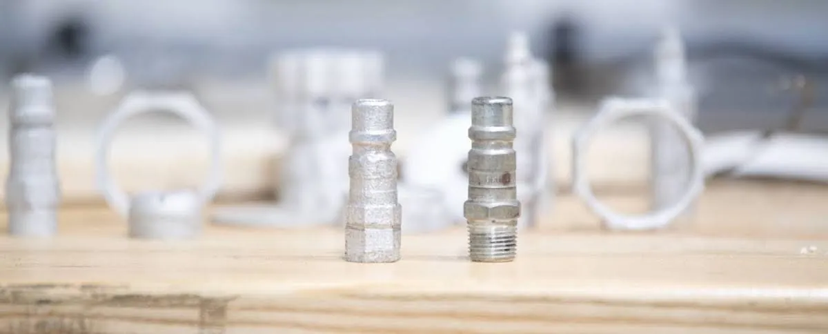 Several narrow cylindrical parts stand near wider, circular parts. The cylindrical parts have different thicknesses, threads for screwing into place, and small openings. 