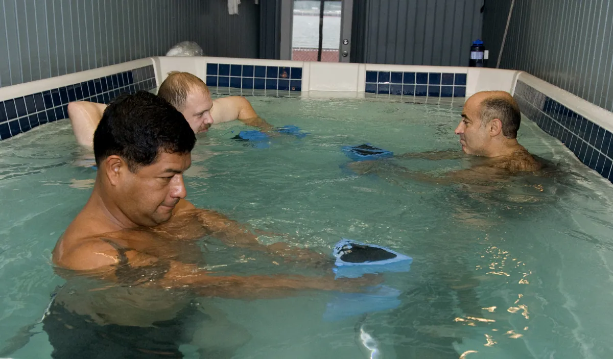 Three men in a hydrotherapy pool.
