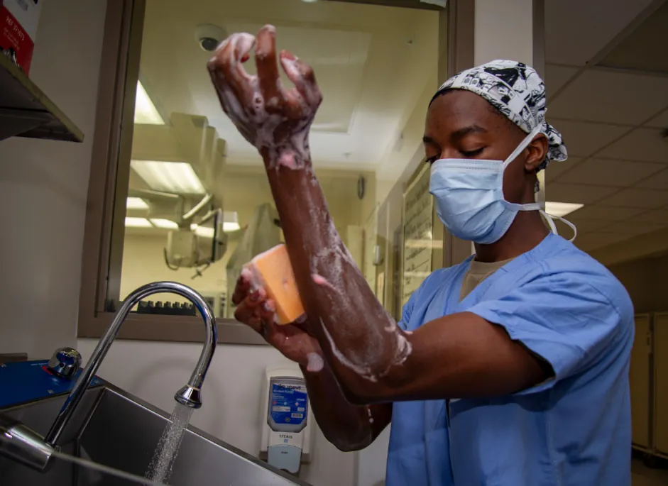 A photograph of a medical team member outside the operating room watching his hands and arms thoroughly.