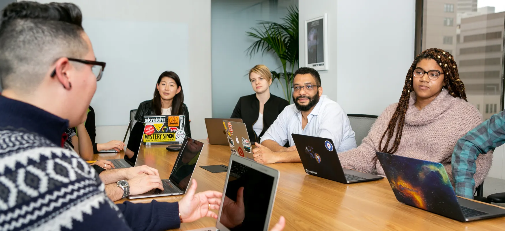 Five people with laptops at a conference table.