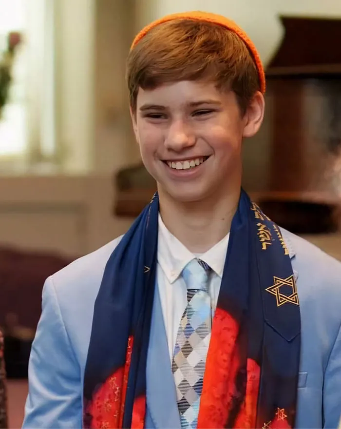 An adolescent is shown smiling at his bar mitzvah.