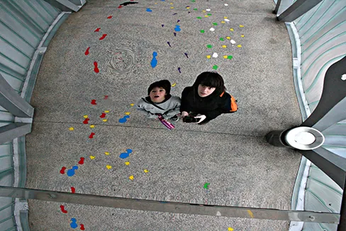 A photograph of two children staring at themselves in a distorting mirror.