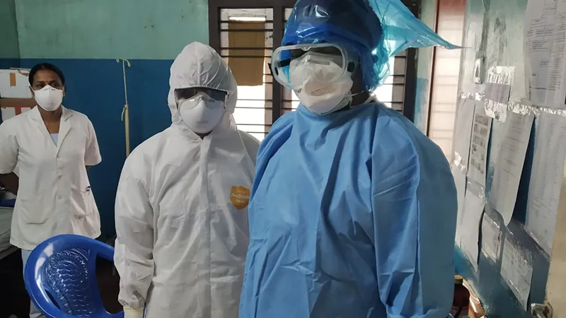 Three healthcare workers stand in a hospital wearing PPE (personal protective equipment) during the Covid pandemic.