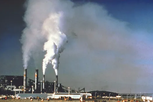 An image of a power plant with large columns of smoke billowing out of its four towers.