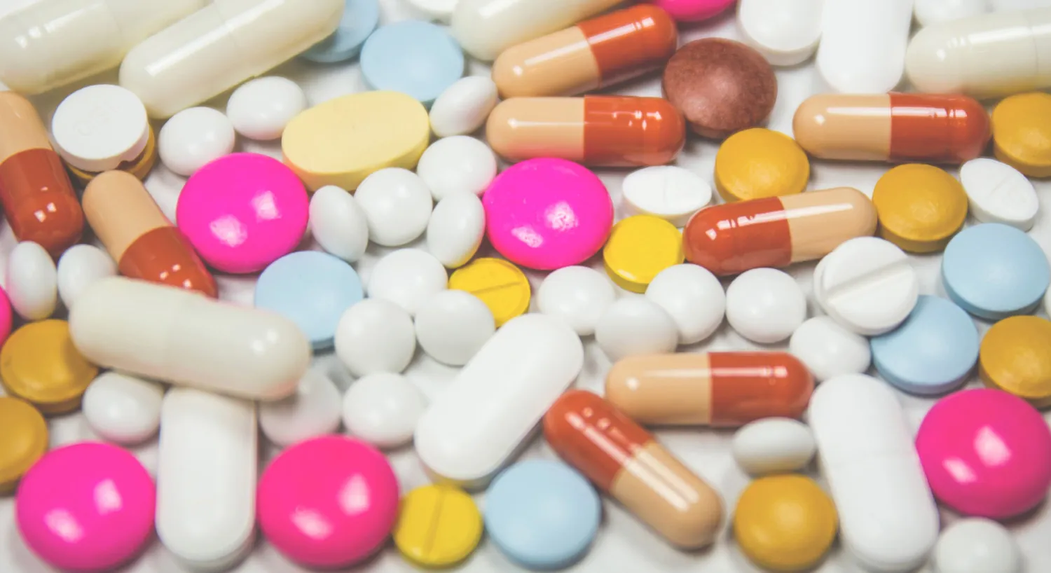 Photo of medications spread out in a variety of colors, shapes, sizes, and types.