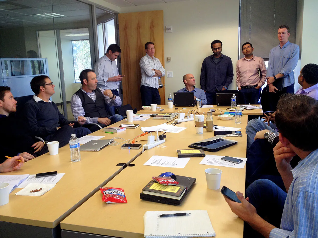 A photo shows a group of coworkers discussing during a meeting in an office.